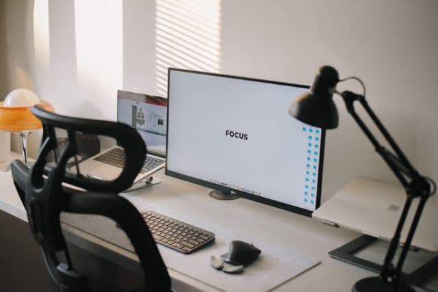 Software engineer's remote workstation with code editor, video call, and project board visible across screens