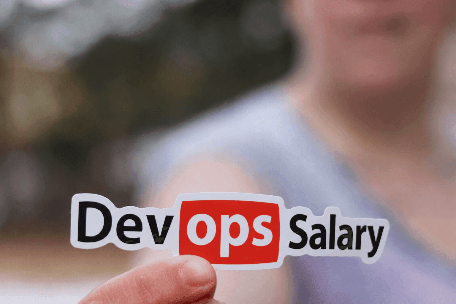 Remote DevOps engineer reviewing salary chart on dual monitors with a cloud infrastructure diagram